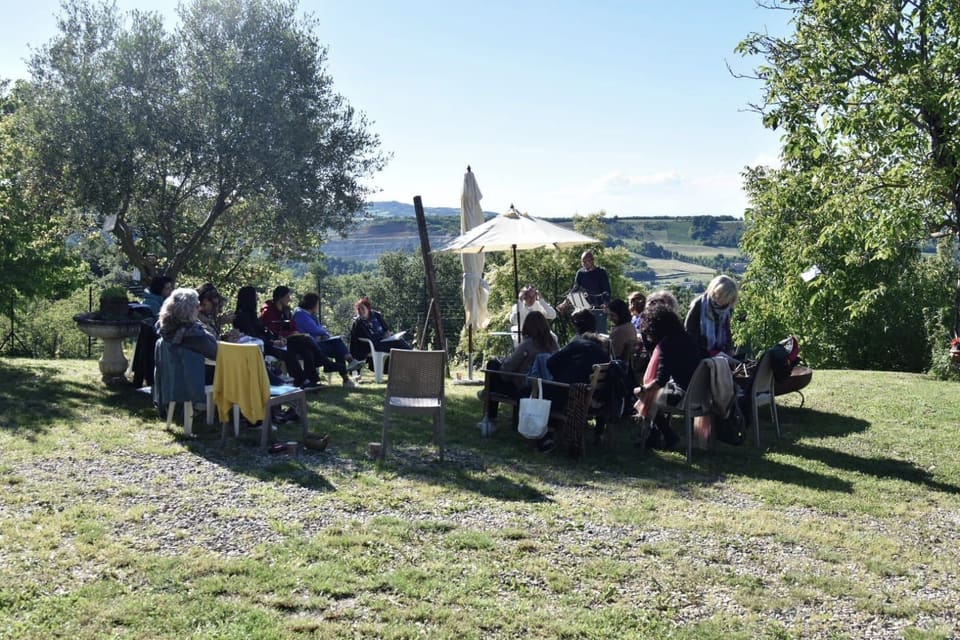 Un incontro all’aperto, seduti in cerchio sul prato, con le colline sullo sfondo.