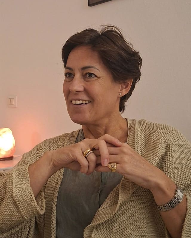 Maria Cristina Iaselli, sorridente al tavolo della lezione con il quaderno degli appunti aperto.