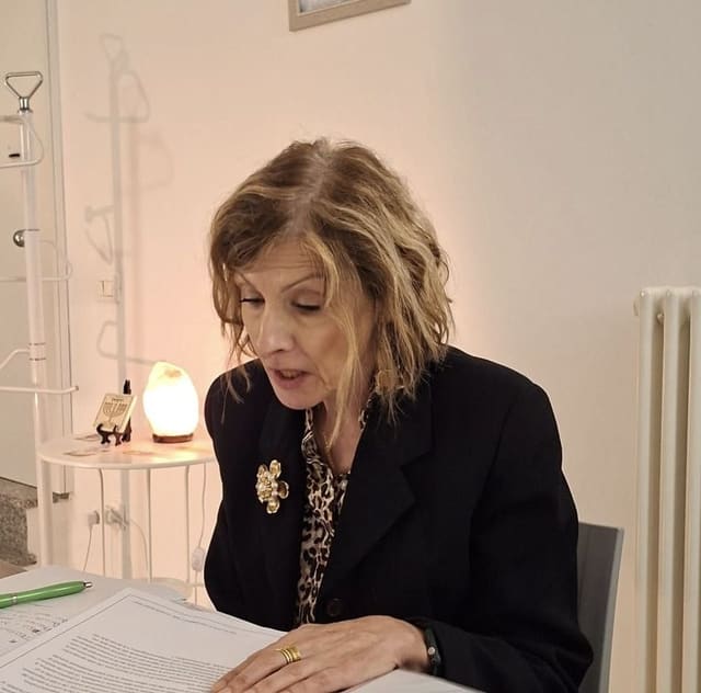 Maria Grazia Ferrario legge le schede del corso al tavolo della sala.